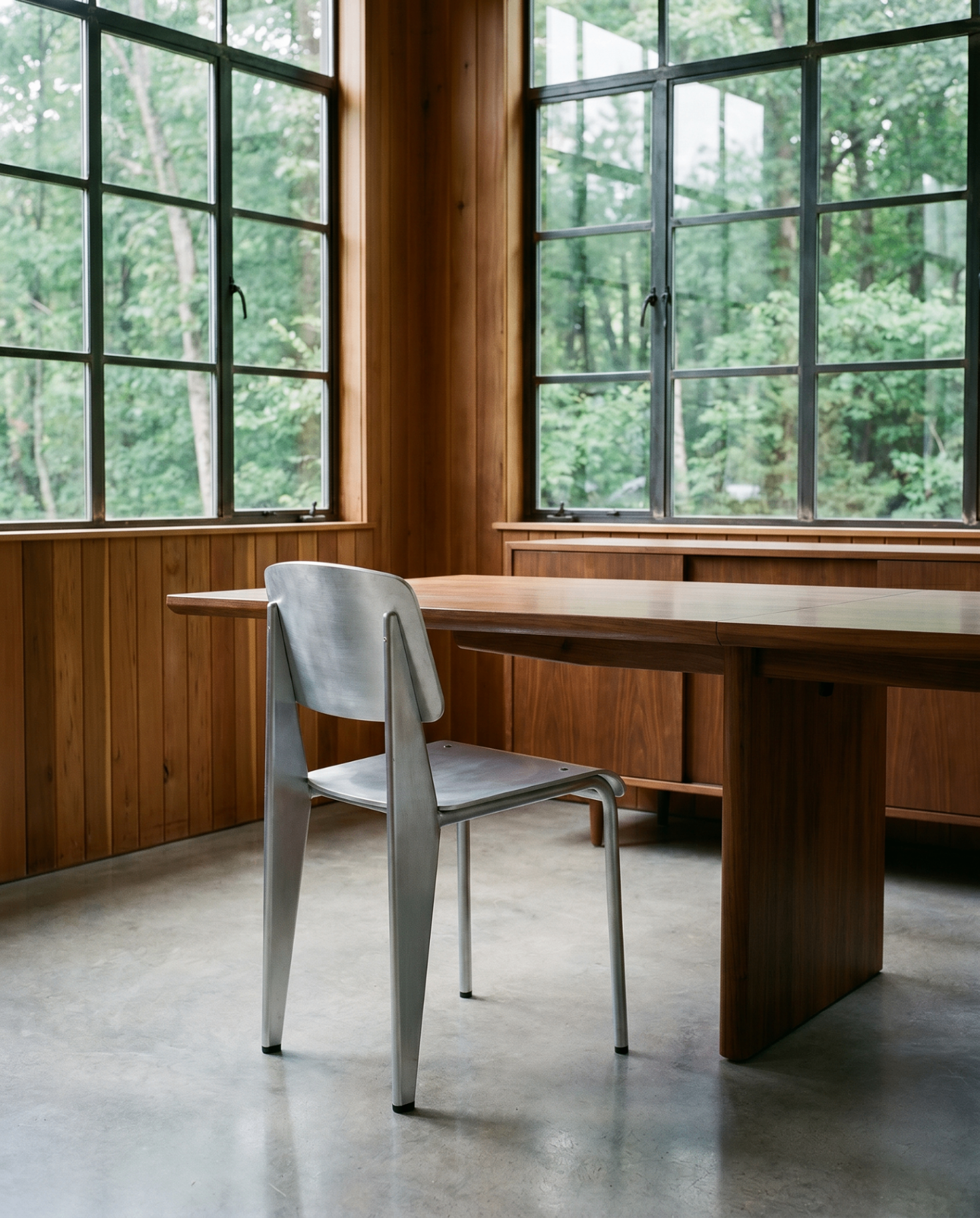 Brushed aluminum Jean Collection chair in a cedar and walnut panelled dining room
