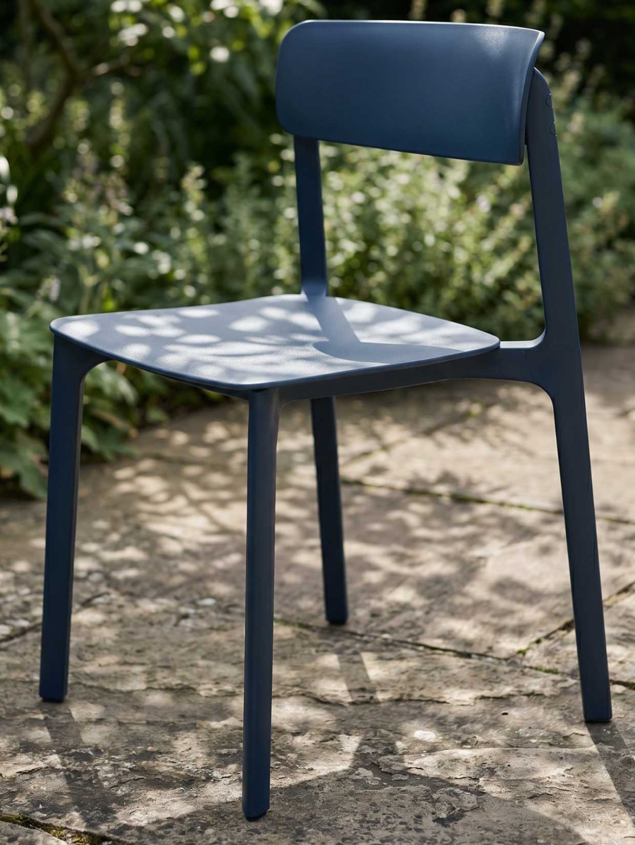Matte navy blue Aero dining chair on a stone patio